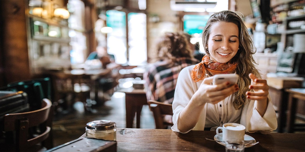 young woman smiling using smartphone in cafe
