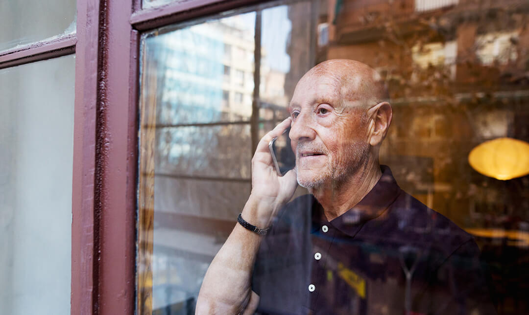 A man staring out of a window whilst on a phone call.